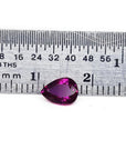 1.00-carat natural pear-shaped ruby gemstone, deep red, next to a ruler for scale.