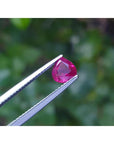 1.19 carat pear cut natural ruby gemstone, sparkling medium deep red, held in tweezers.
