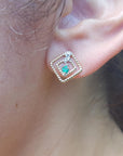 close up of a 14K yellow gold emerald post earring with round cut Colombian emerald set in a double frame rope decoration.