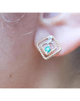 close-up of an emerald earring with double rope frame on an earlobe.