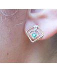 close-up of an emerald earring with double rope frame on an earlobe.