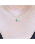 Pear-shaped natural emerald necklace with diamond halo on 14K yellow gold chain.