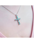 18K white gold cross pendant with eleven round-cut Colombian emeralds on a delicate chain.