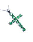 A 18k white gold emerald cross pendant necklace on a toside position view.