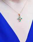 Necklace with a floral natural emerald cross pendant on a blue garment.