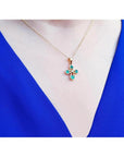 Emerald cross pendant with round-cut emeralds and a diamond accent, crafted in 18K yellow gold.
