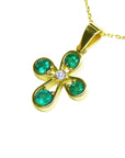 Gold necklace with a four-leaf cross pendant featuring natural colombian emeralds round cut each leaf.