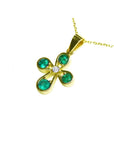 Yellow gold flower pendant with four round emeralds and a center diamond on a delicate chain.