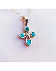 Emerald cross pendant with round-cut emeralds and a diamond in 18K yellow gold.
