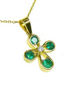 Gold necklace with a crossr-shaped pendant featuring natural emeralds on a right-side top position view.