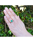 18K yellow gold ring with a GIA certified emerald and side trillion diamonds on a hand.