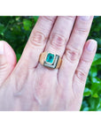 Men's 18K yellow gold ring with a rectangular emerald and channel-set princess-cut diamonds.