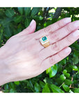 Hand wearing a 18k yellow gold ring for men with a natural colombian emerald.