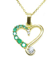 Gold heart-shaped pendant with natural round cut emeralds and diamond on a top profile view.