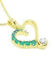 Gold heart-shaped pendant with natural emeralds and diamond on a topside view position.