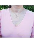 Emerald and diamond heart pendant in 18K yellow gold on a woman's neck.