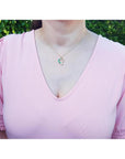 Emerald and diamond heart pendant in 18K yellow gold on a woman's neck.