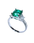 A 18k white gold women's natural cushion cut emerald and diamond ring, half lateral profile view.