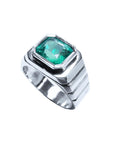 This mens solitaire ring in white gold shows the top bezel set colombian emerald and partial perspective sides decoration.