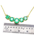 14K gold necklace with five round, medium green Colombian emeralds, measured by a ruler.