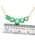 14K gold necklace with five round, medium green Colombian emeralds, measured by a ruler.