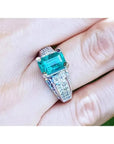 Anillo de mujer con esmeralda colombiana verde profundo y diamantes en oro blanco de 18K, estilo antiguo.