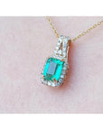 Emerald cut Colombian emerald slider pendant with halo diamonds on a 14K gold chain.
