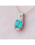 Emerald cut Colombian emerald slider pendant with halo diamonds on a 14K gold chain.