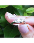 14K white gold engagement ring with a round center diamond and two trillion side diamonds.