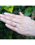 14K white gold engagement ring with a round center diamond and trillion side diamonds on a hand.