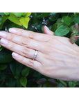14K white gold engagement ring with a round center diamond and trillion side diamonds on a hand.