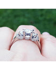14K white gold three-stone engagement ring with round cut natural diamonds and pave set accents.
