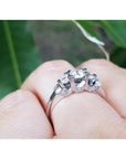 14K white gold three-stone round cut diamond engagement ring with pave set accent diamonds.