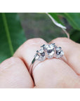 14K white gold three-stone round cut diamond engagement ring with pave set accent diamonds.