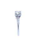 White gold engagement ring with a round central diamond and baguette side diamonds.