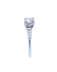 White gold engagement ring with a round central diamond and baguette side diamonds.