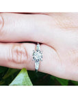 14k white gold engagement ring with round diamond and baguette side stones on a finger.