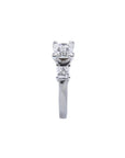 White gold 14K three-stone ring with a central princess cut diamond flanked by two smaller princess cut diamonds.