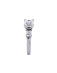 White gold 14K three-stone ring with a central princess cut diamond flanked by two smaller princess cut diamonds.