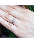 Princess cut three-stone diamond ring in 14K white gold on a hand.