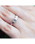 14K white gold three-stone ring with princess cut diamonds on a hand.