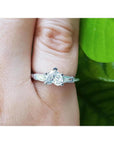 14K white gold heart cut diamond ring with side tapered baguette diamonds on a finger.