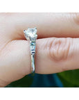 14K white gold ring with a heart-cut diamond center stone and side baguette diamonds on a finger.