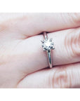Round cut diamond solitaire engagement ring in 14K white gold, worn on a finger.