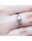 Round cut diamond solitaire engagement ring in 14K white gold, worn on a finger.