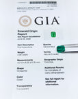 Untreated GIA emerald origin report with green emerald stones on a white background.