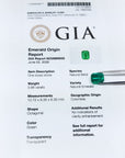 Untreated GIA emerald origin report with green emerald stones on a white background.