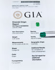 Untreated GIA emerald origin report with green emerald stones on a white background.