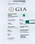 Untreated GIA emerald origin report with green emerald stones on a white background.