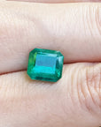 A GIA certified F1 natural colombian loose emerald held between fingers